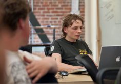A programmer reviewing lines of code on a large monitor in a dim office.
