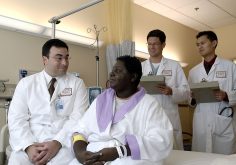 Doctors in white coats talking with a woman patient in a hospital room