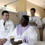 Doctors in white coats talking with a woman patient in a hospital room