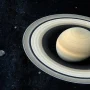 Saturn and its rings surrounded by many small moons in deep space